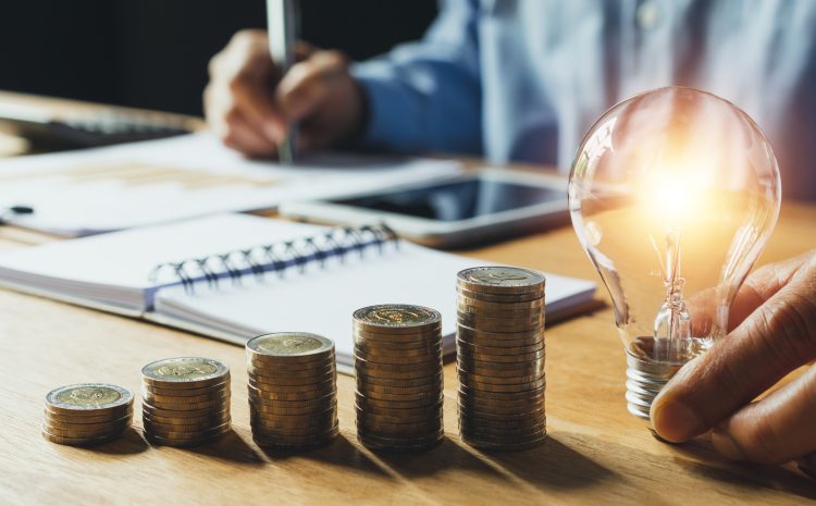 Business man holding light bulb on the desk in office and writin