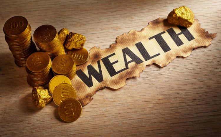 Wealth written on vintage paper and stack of gold coins and gold rocks